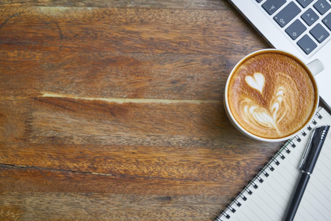 Latte art heart beside a notebook
