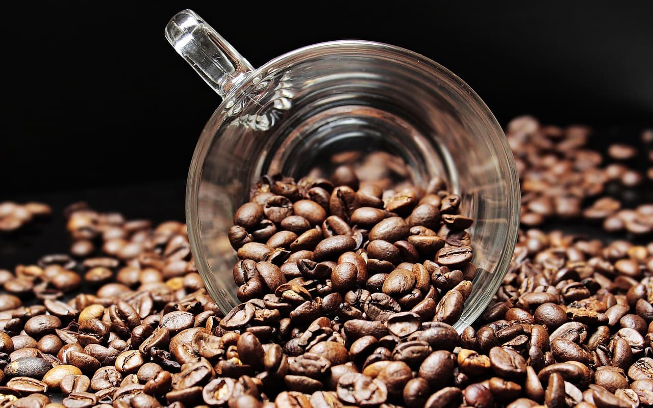 Coffee beans spilling from a glass cup