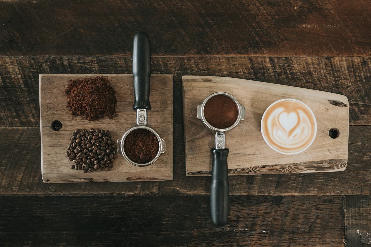 Espresso and a latte with ground coffee on a board