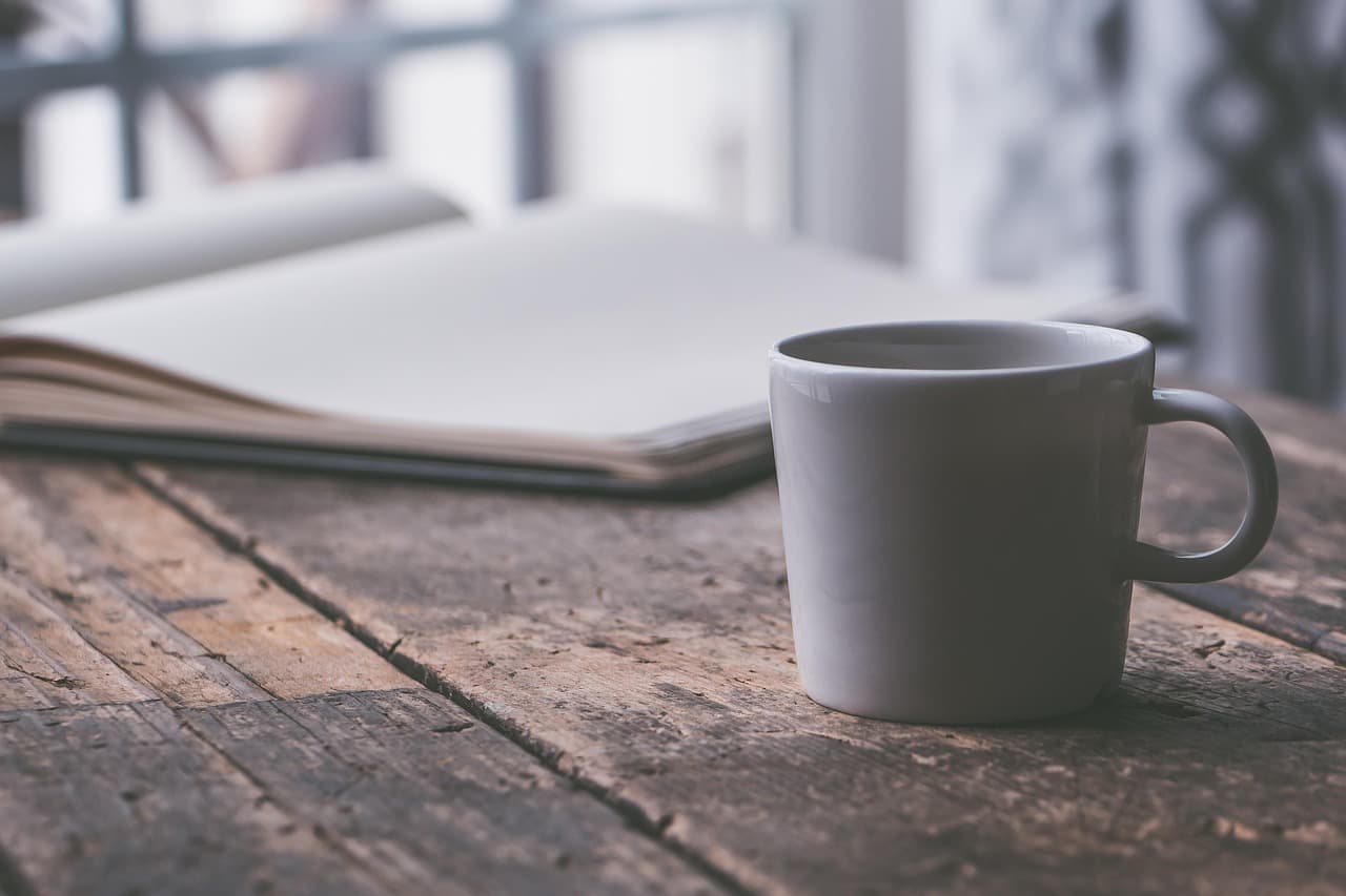 Mug of coffee beside an open notebook