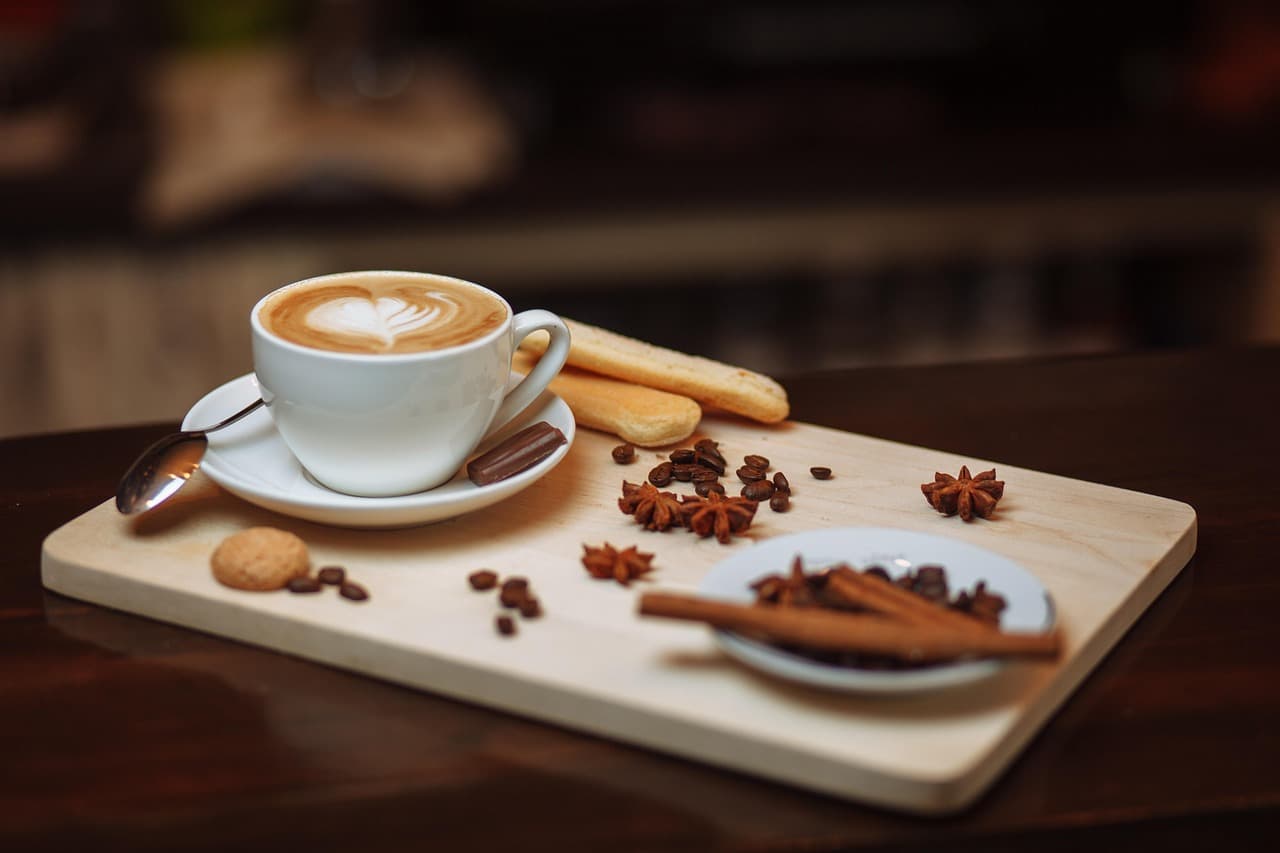 Cappuccino with biscuits and cinnamon on a wooden board